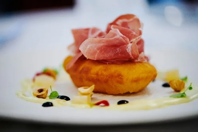Pizza soufflée, jambon de Parme, poires confites, noisettes et crème de parmesan